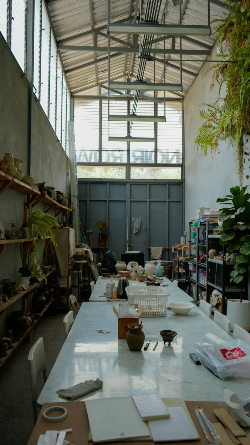 Taller de cerámica con herramientas y arte sobre un banco de trabajo.