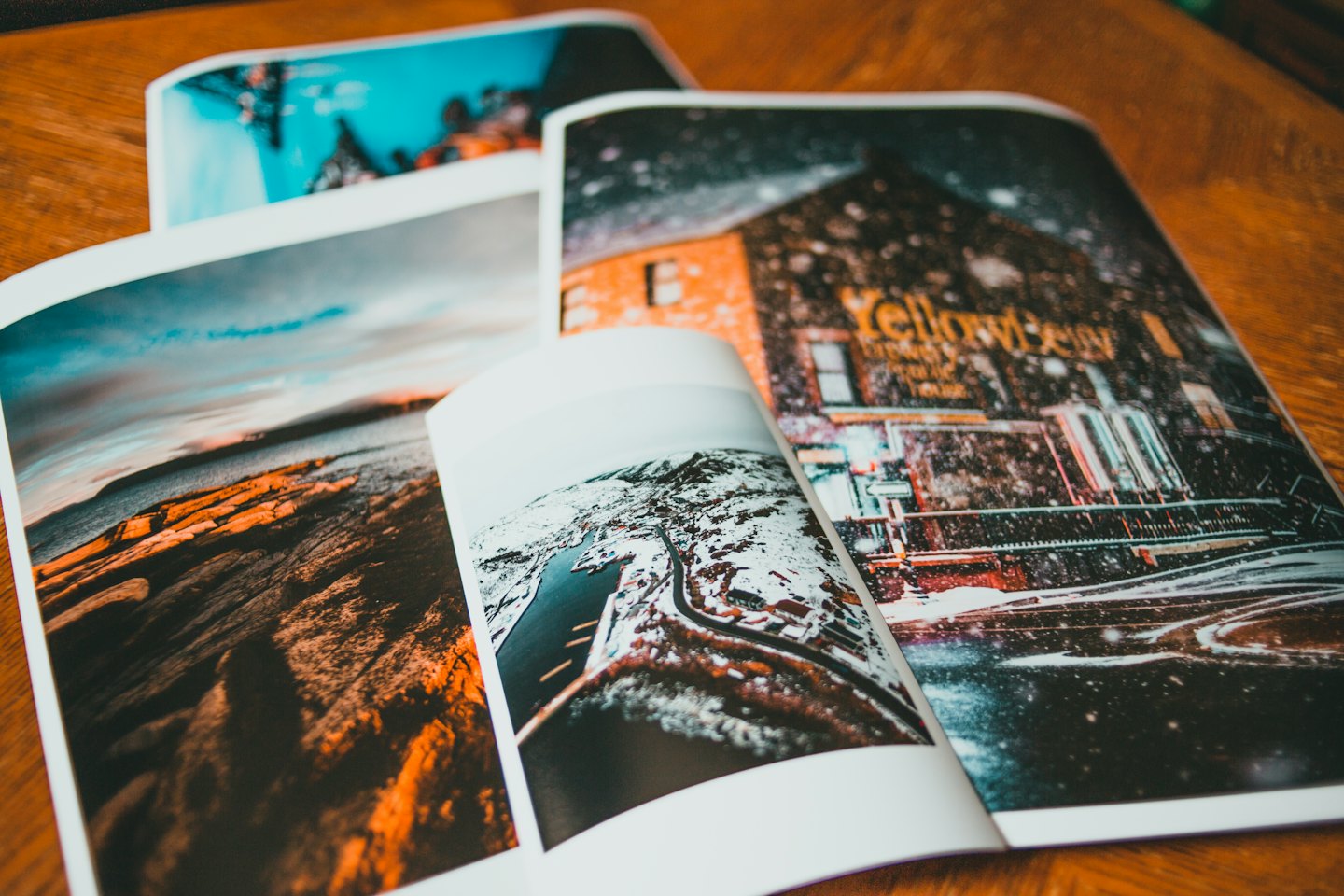 Revistas abiertas exhiben fotografía sobre una mesa de madera.