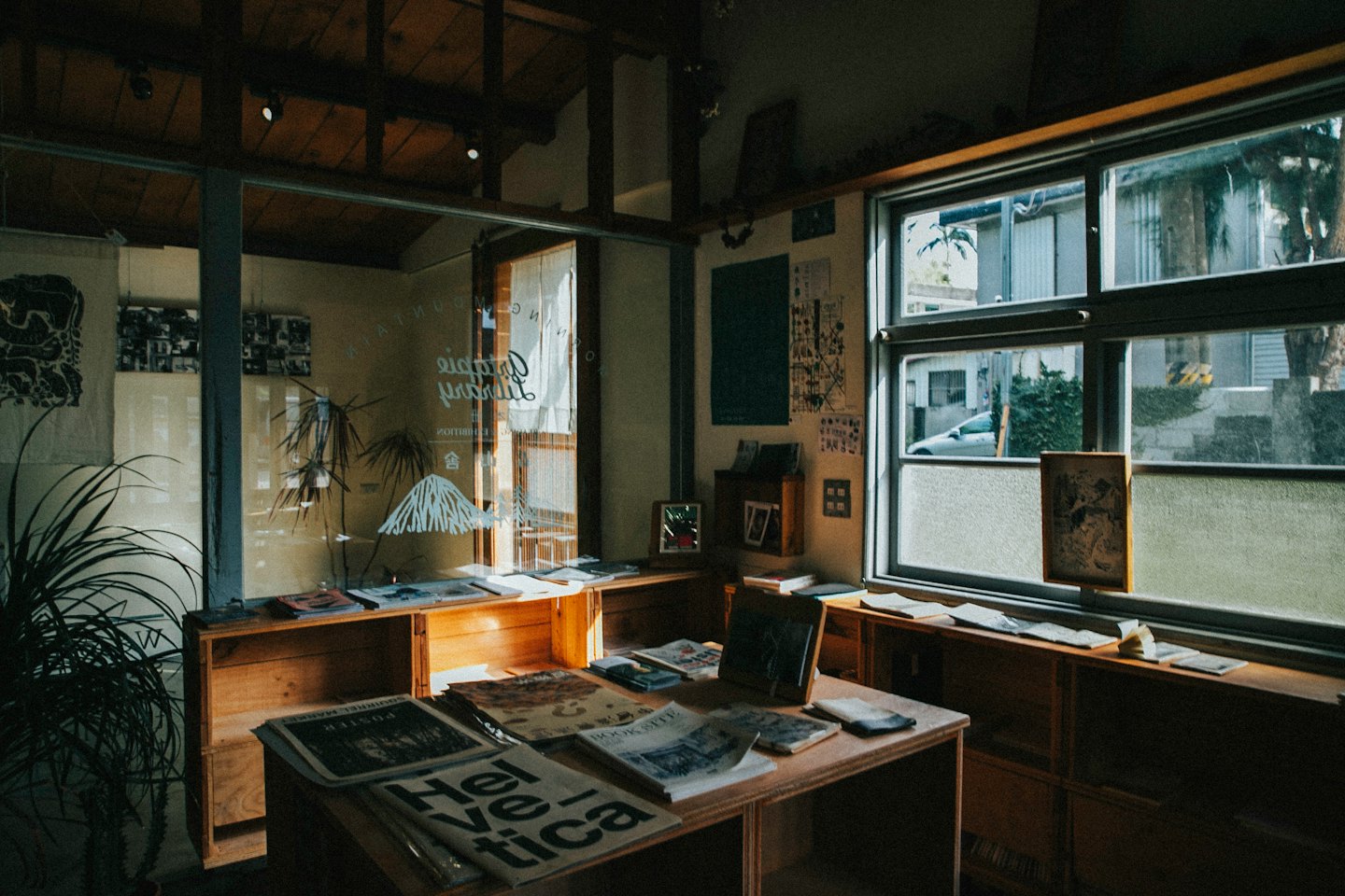 Libros y revistas expuestos en estanterías y mesas rústicas de madera.