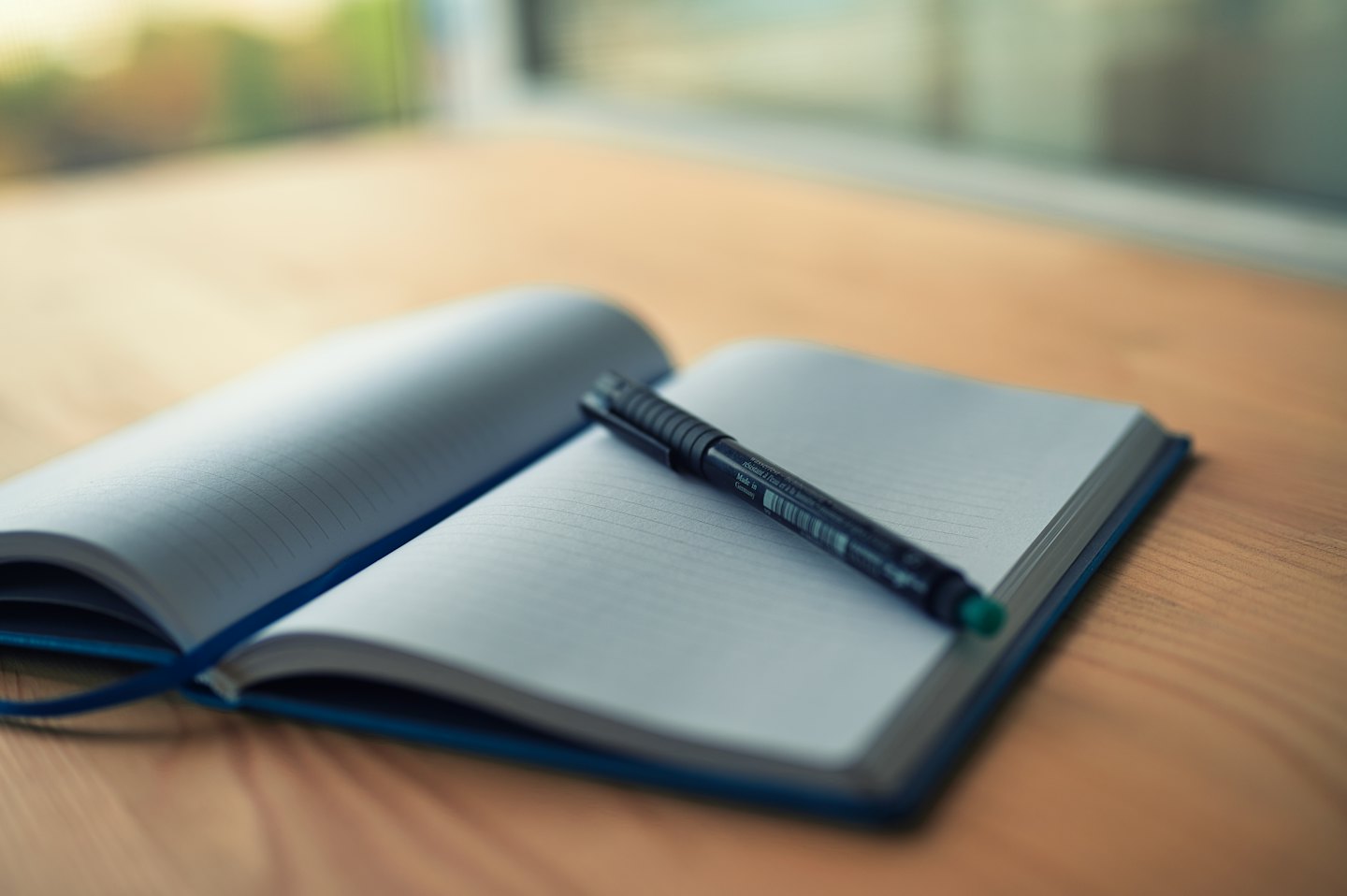 Una libreta abierta y un bolígrafo negro sobre una mesa de madera.